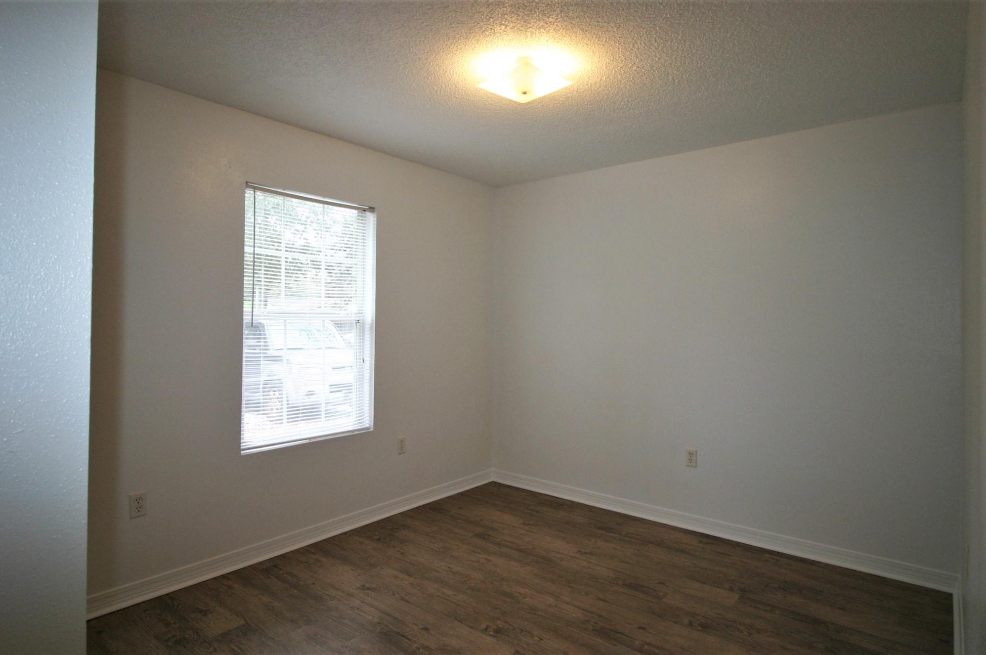 532 Brock Avenue Crestview, FL 32539 - Photo 6 of 10 an empty room with wooden floor and windows