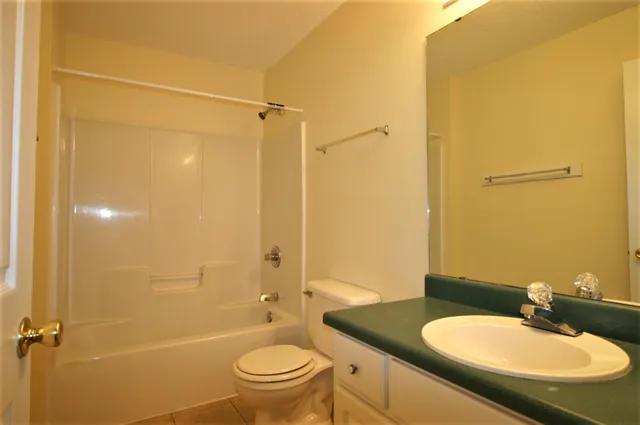 a bathroom with a granite countertop sink toilet mirror and shower