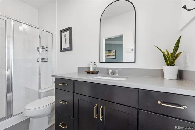 a bathroom with a granite countertop sink a toilet and with mirror