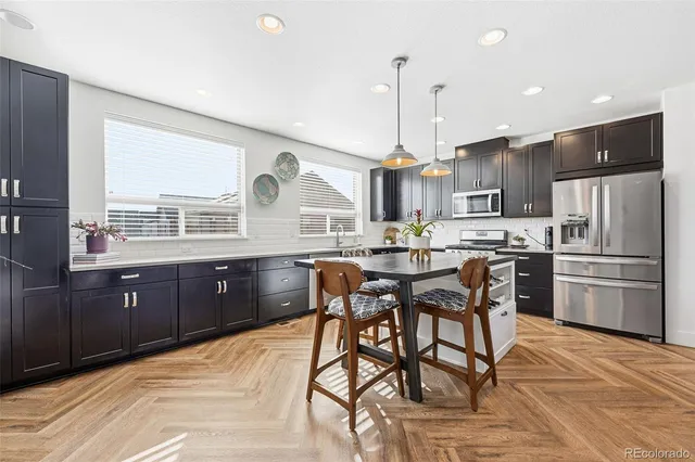 a kitchen with stainless steel appliances kitchen island granite countertop a table chairs and a refrigerator