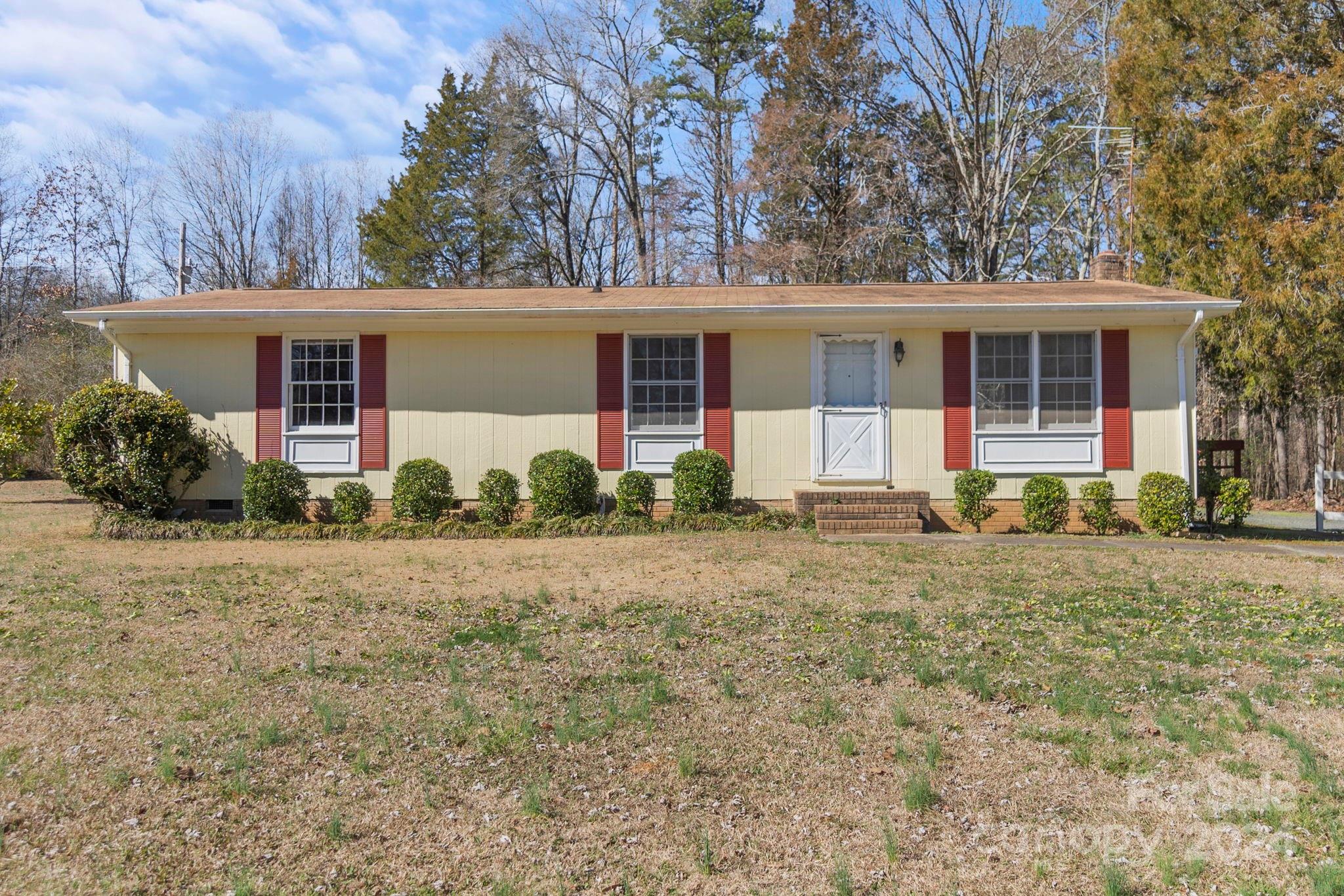 a front view of house with yard and trees in the background