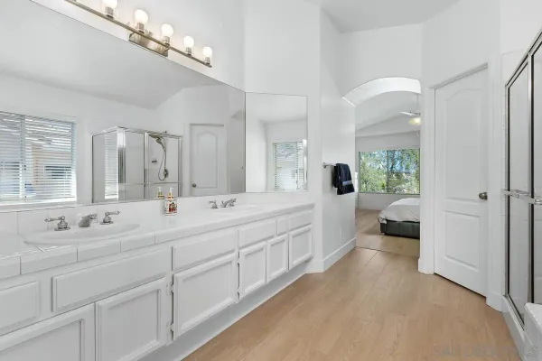 a spacious en suite bathroom with a double vanity sink a mirror and a shower