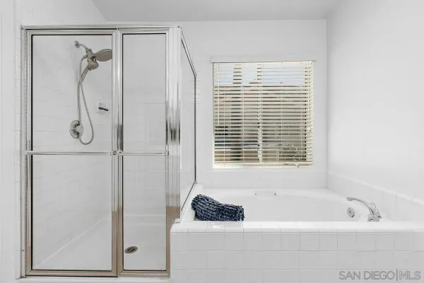a bathroom with a bathtub a shower and a window