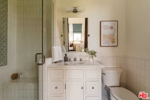 a bathroom with a toilet sink vanity and mirror