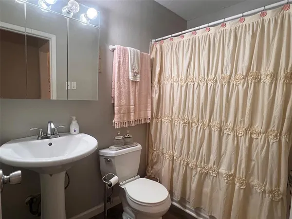 a bathroom with a sink a toilet and shower curtain