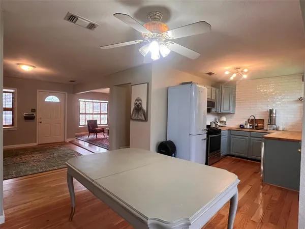 a kitchen with stainless steel appliances kitchen island granite countertop a refrigerator a stove top oven a sink dishwasher and white cabinets with wooden floor