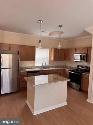 a kitchen with stainless steel appliances granite countertop a sink a stove a refrigerator and island with wooden floor