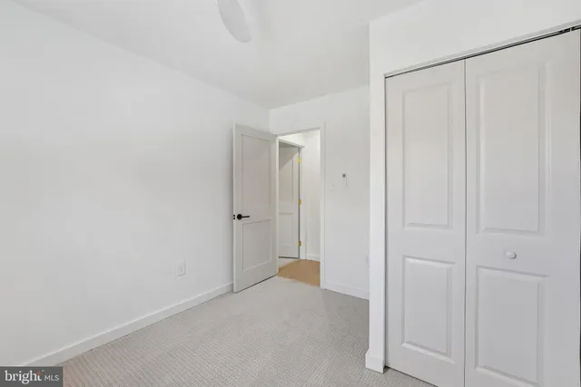 an empty room with a ceiling fan and carpet