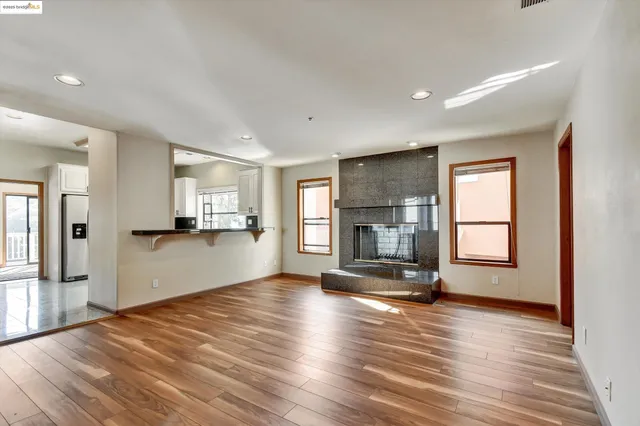 a view of empty room with wooden floor and a kitchen