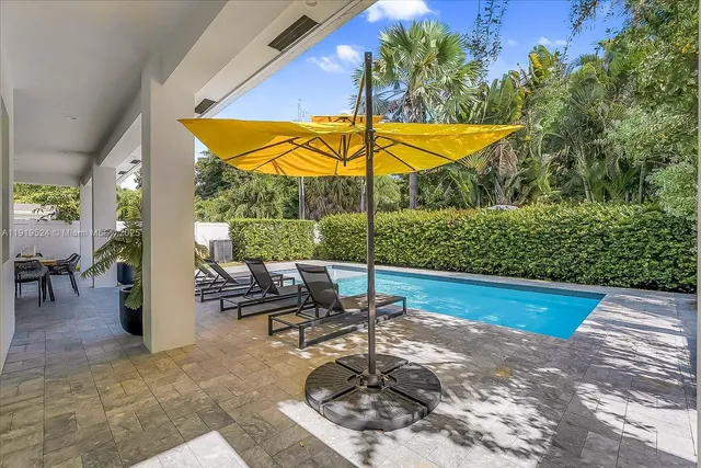 a view of swimming pool with lawn chairs and plants
