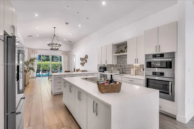 a kitchen with a stove a sink a refrigerator and a dining table with wooden floor