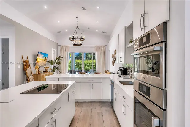 a kitchen that has a lot of white cabinets and stainless steel appliances