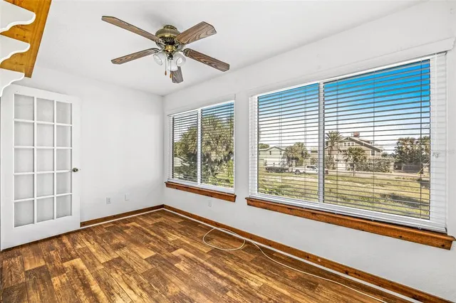 a view of empty room with wooden floor and fan