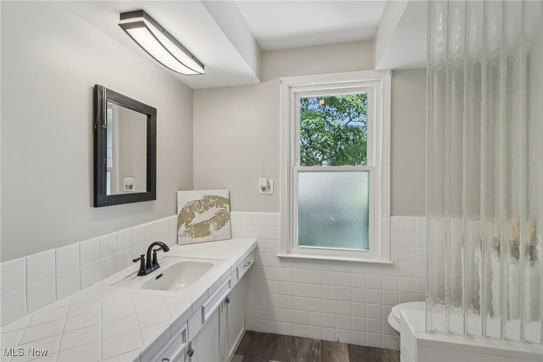 128 Overwood Road Akron, OH 44313 - Photo 31 of 40 Full bath with tile walls, vanity, wainscoting, wood finished floors, and a shower with curtain
