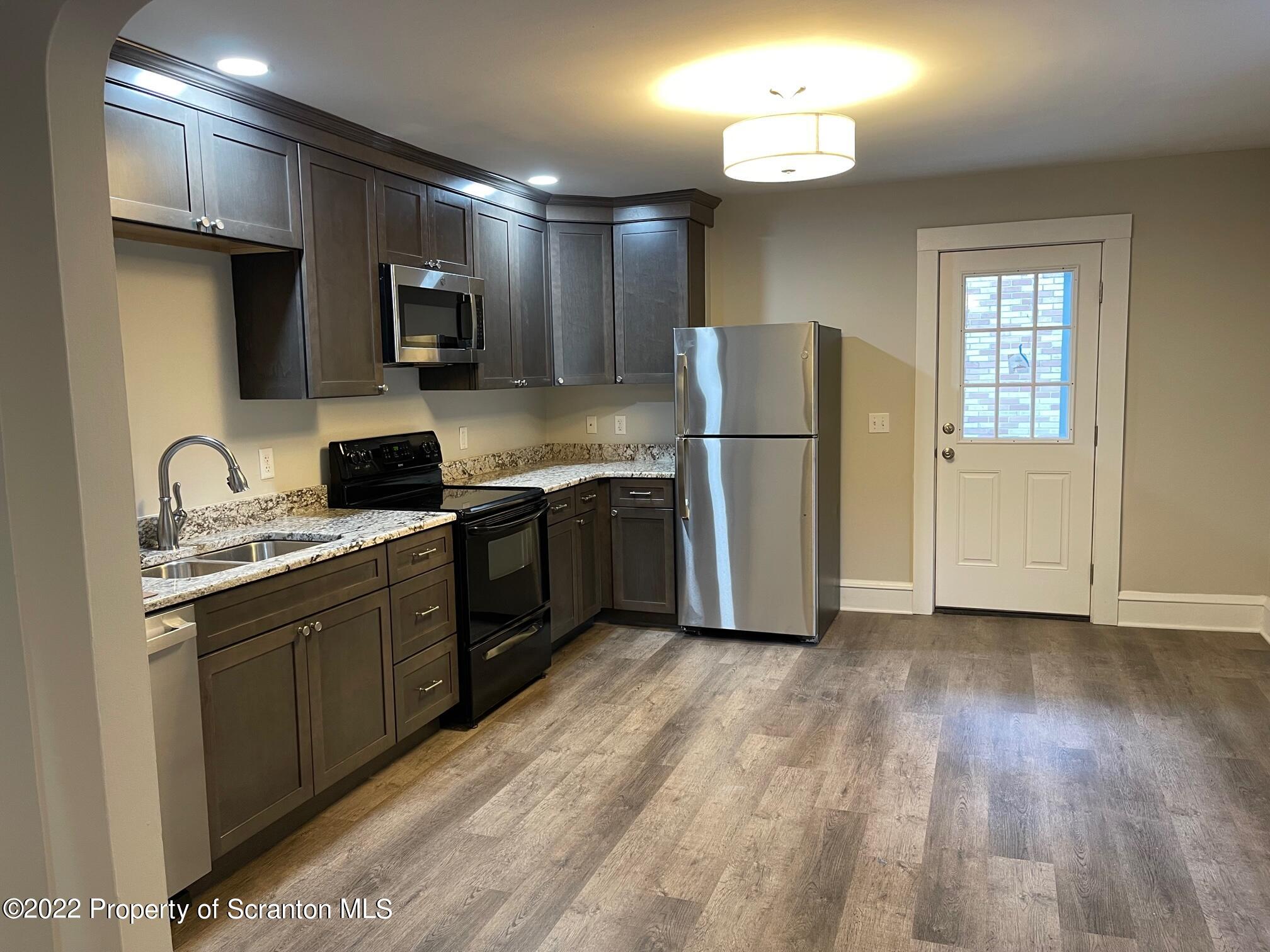 1833 South Webster Avenue Scranton, PA 18505 - Photo 8 of 17 a kitchen with stainless steel appliances granite countertop a refrigerator a sink dishwasher a stove and white countertops with wooden floor