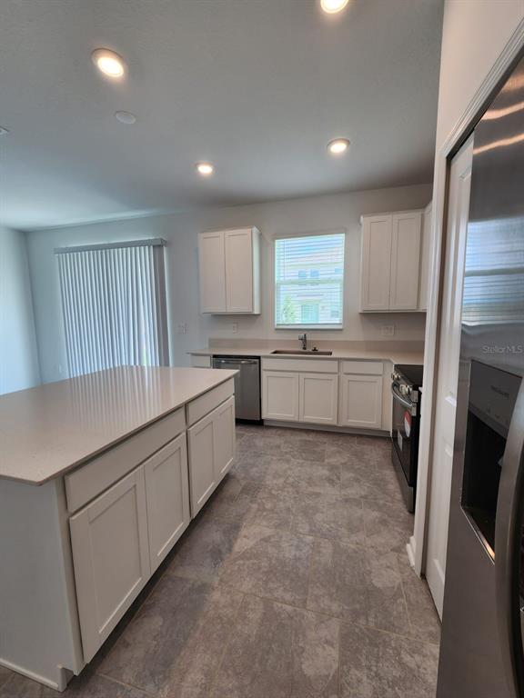 3258 Laurent Loop Davenport, FL 33837 - Photo 4 of 26 a kitchen with white cabinets and white appliances