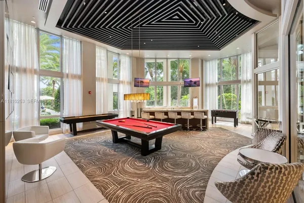 a room with furniture pool table and glass windows