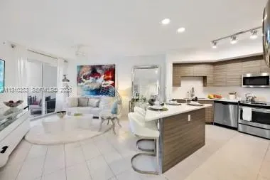 a large white kitchen with stainless steel appliances kitchen island granite countertop a sink and cabinets