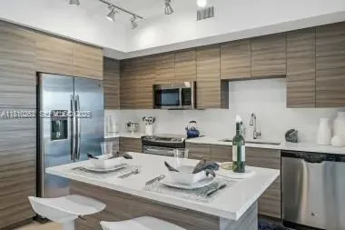 a kitchen with granite countertop kitchen island stainless steel appliances a sink and a refrigerator