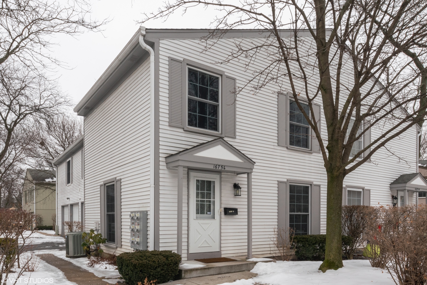 1675 Valley Forge Court, Unit E Wheaton, IL 60189 - Photo 1 of 11 a front view of a house with a garden