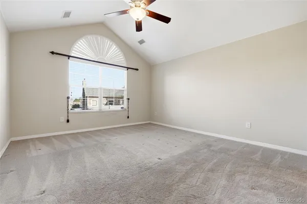 an empty room with a chandelier fan and windows