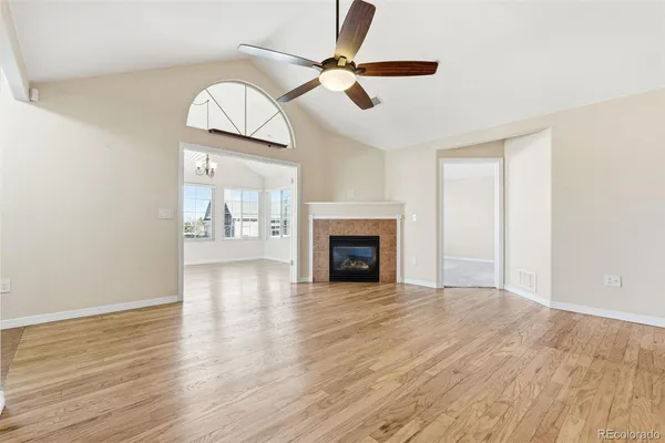 an empty room with wooden floor fireplace and windows