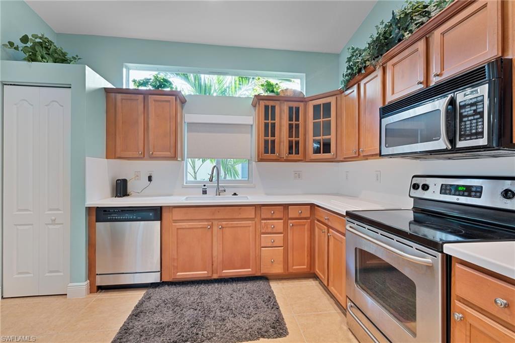 15322 Cortona Way Naples, FL 34120 - Photo 4 of 26 a kitchen with stainless steel appliances granite countertop a stove a sink and a microwave