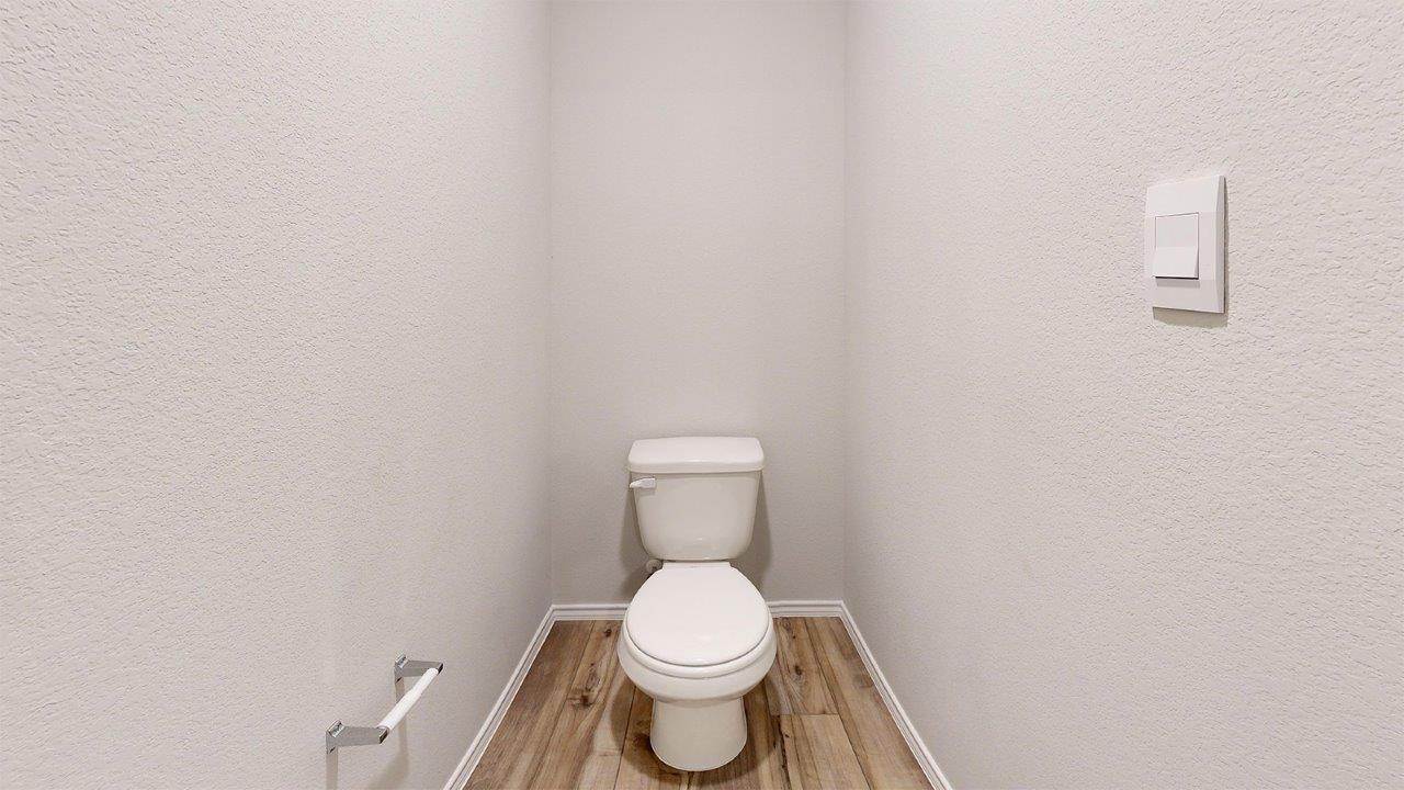 557 Hector Loop Georgetown, TX 78626 - Photo 29 of 38 Private water closet featuring a standard white toilet, wood-finish flooring, and light-toned textured walls