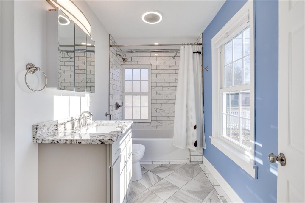 1 Bennett Street Natick, MA 01760 - Photo 19 of 28 a bathroom with a granite countertop sink a large mirror and a bathtub