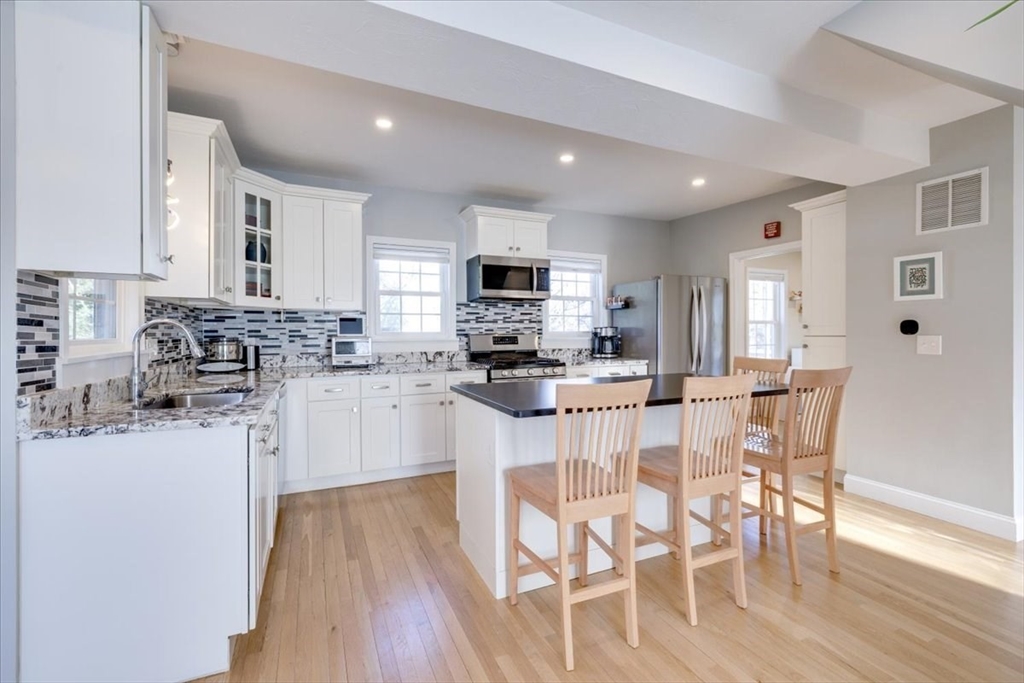 1 Bennett Street Natick, MA 01760 - Photo 6 of 28 a kitchen with stainless steel appliances granite countertop a stove top oven a sink a refrigerator with white cabinets and wooden floor