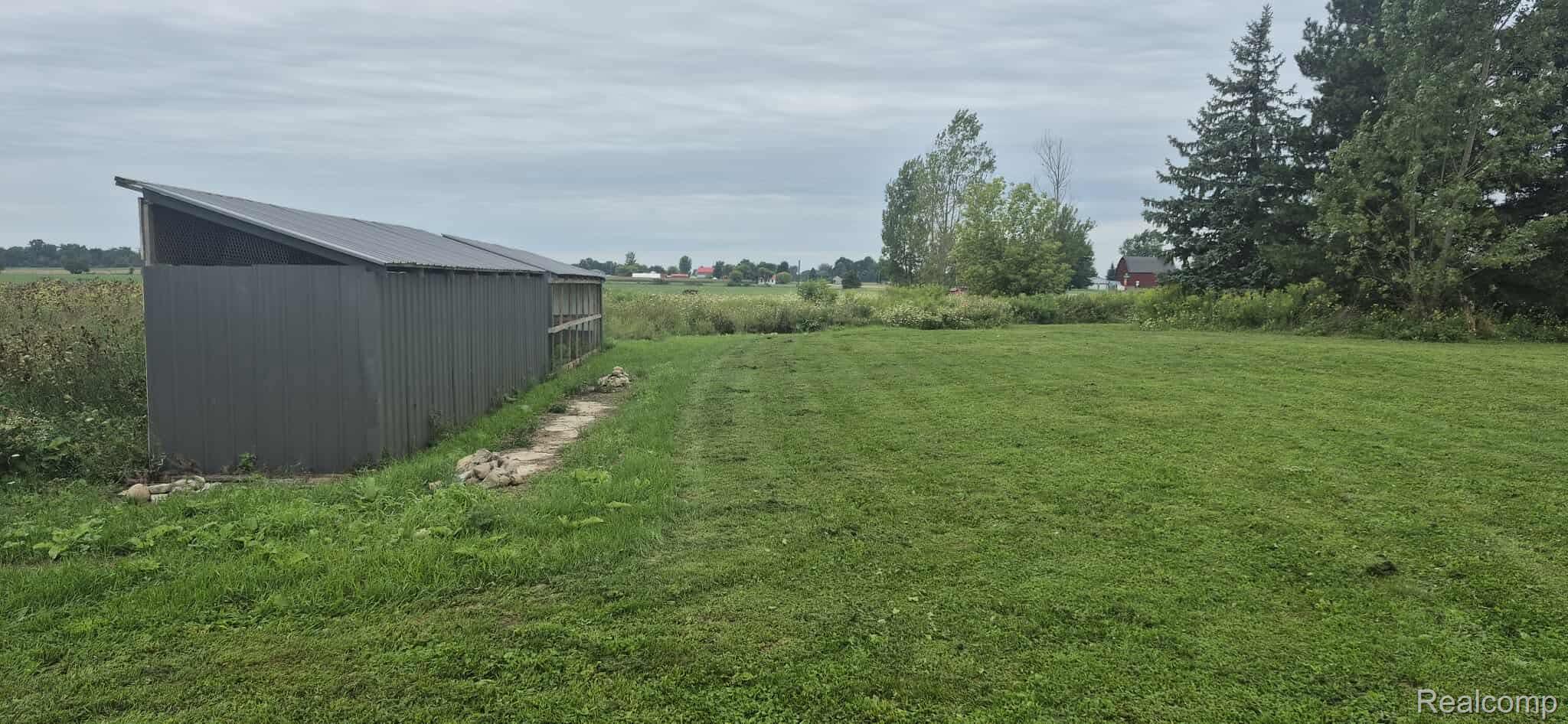 6935 Sanilac Road Marlette, MI 48453 - Photo 8 of 23 View of green lawn featuring a pole building, an outdoor structure, and a rural view