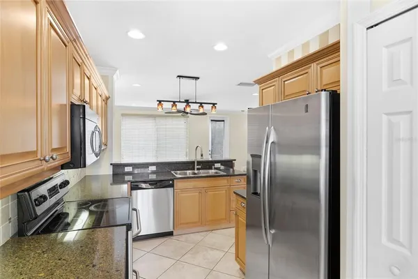 a kitchen with stainless steel appliances granite countertop a refrigerator a stove and a sink