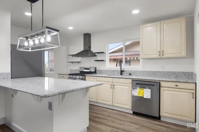 a kitchen with stainless steel appliances granite countertop a sink a stove and a wooden floors