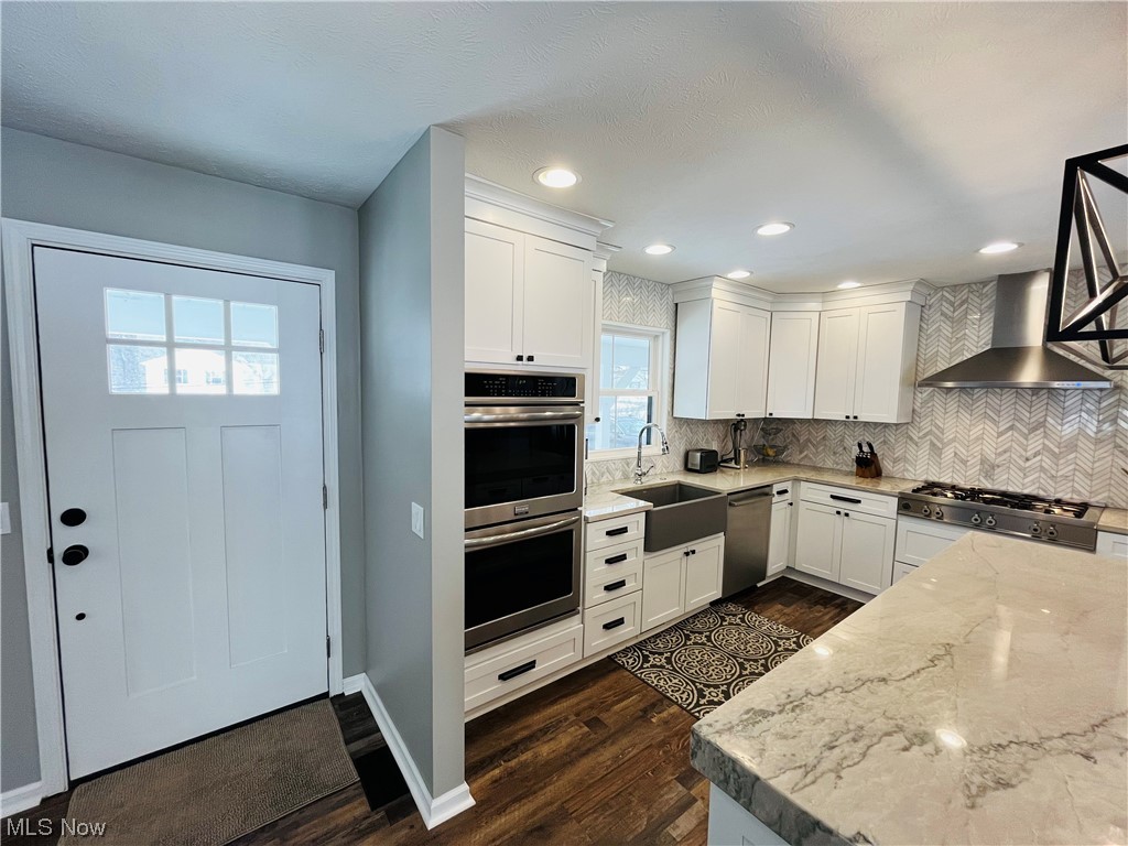 13655 Spring Street Burton, OH 44021 - Photo 19 of 48 Kitchen with wall chimney range hood, appliances with stainless steel finishes, sink, and plenty of natural light
