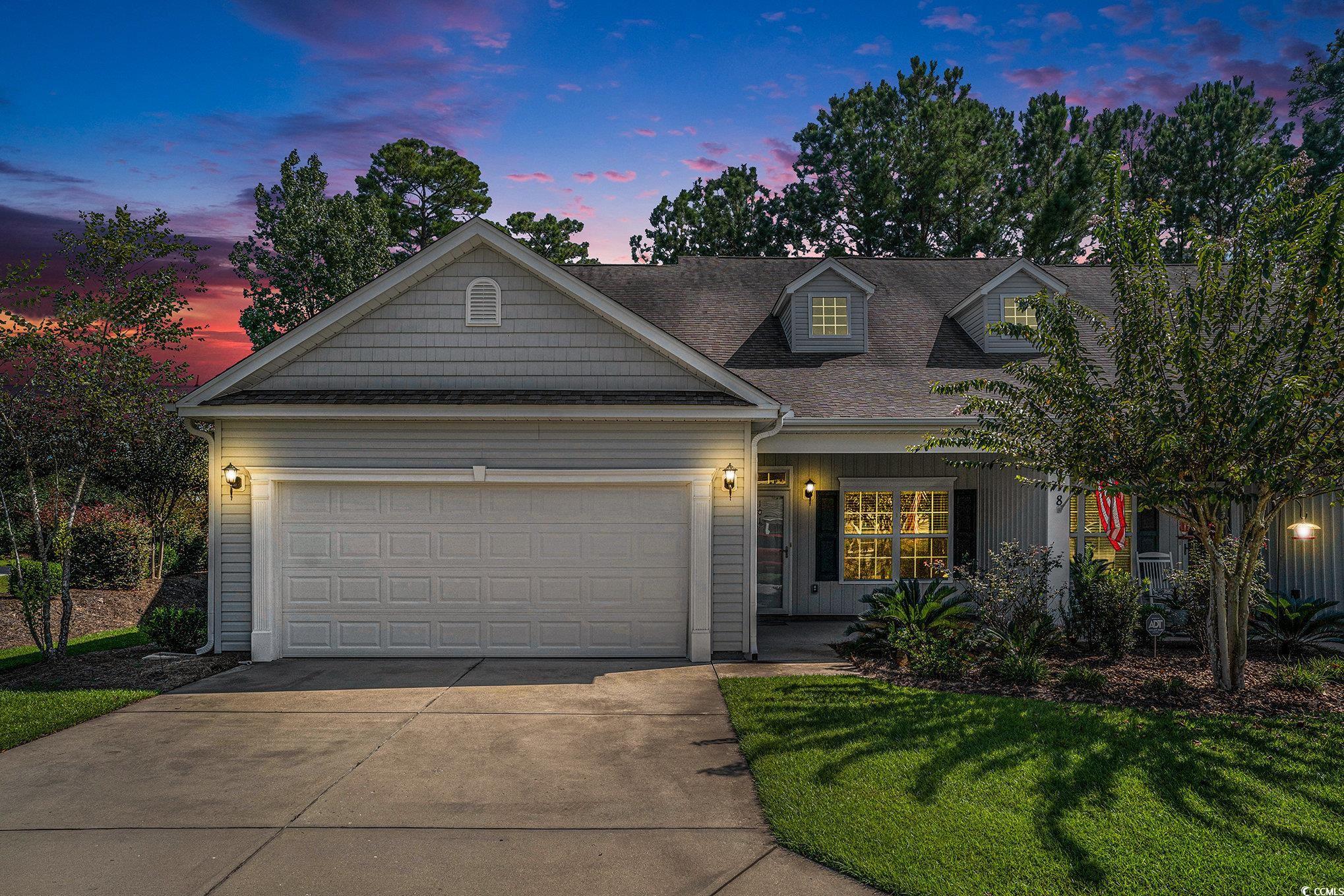 View of front of house with a garage, driveway, a porch, a yard, and roof with shingles