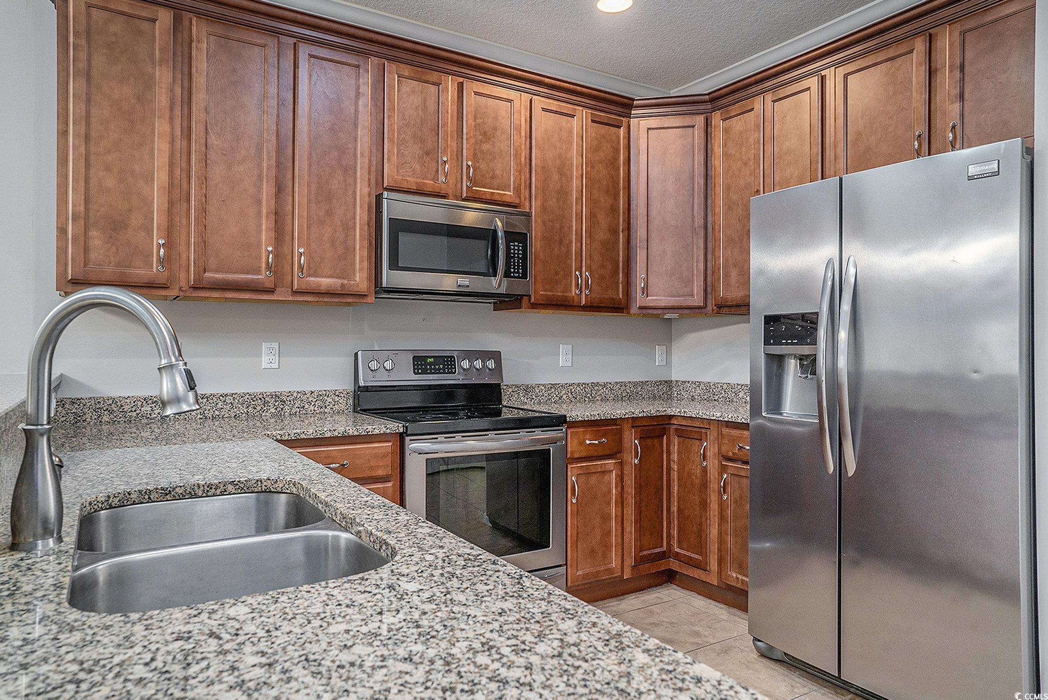 1018 Red Sky Lane, Unit 101 Murrells Inlet, SC 29576 - Photo 13 of 35 Kitchen featuring stainless steel appliances, light stone counters, light tile patterned flooring, brown cabinetry, and recessed lighting