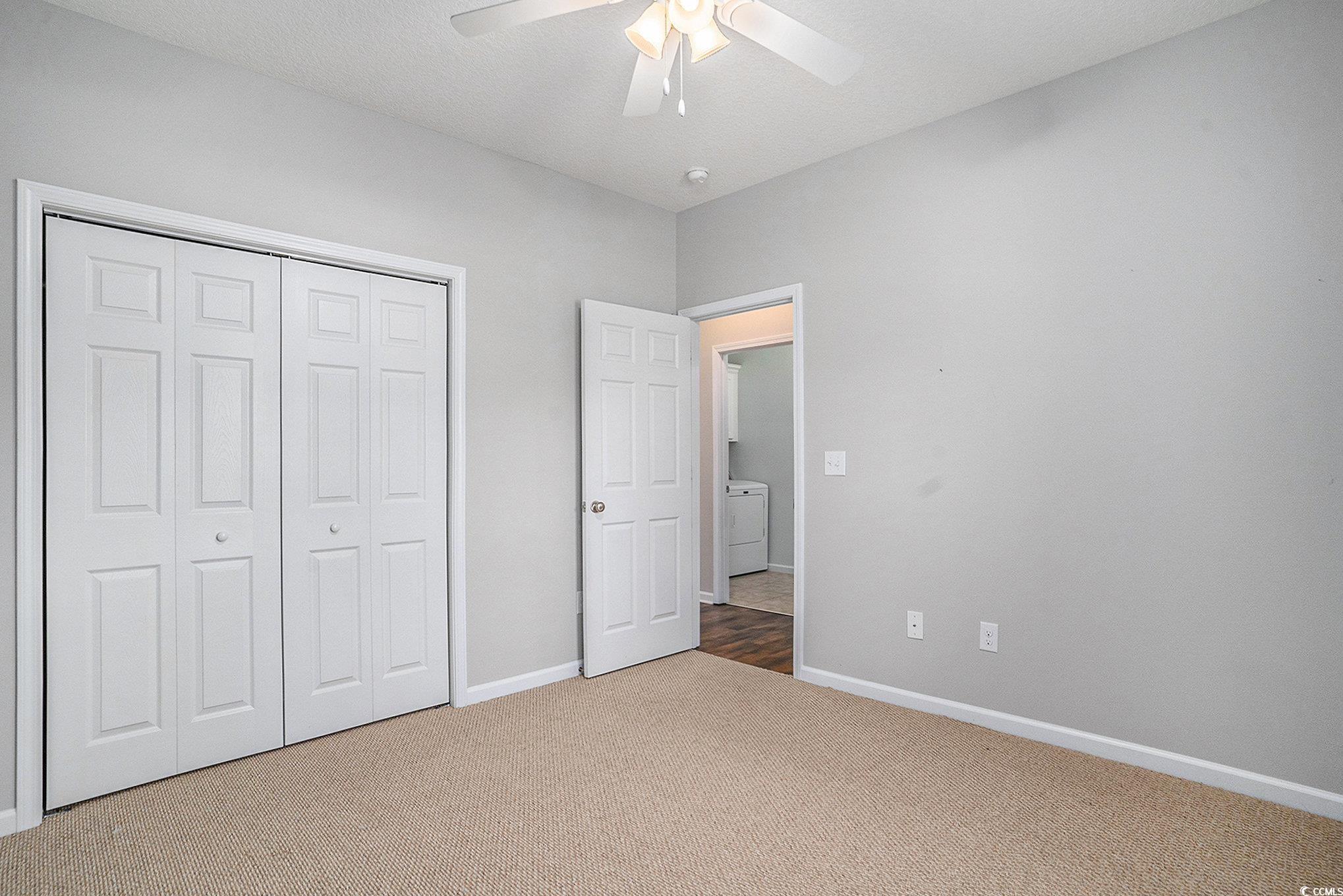 1018 Red Sky Lane, Unit 101 Murrells Inlet, SC 29576 - Photo 25 of 35 Unfurnished bedroom with a closet, light carpet, and a ceiling fan