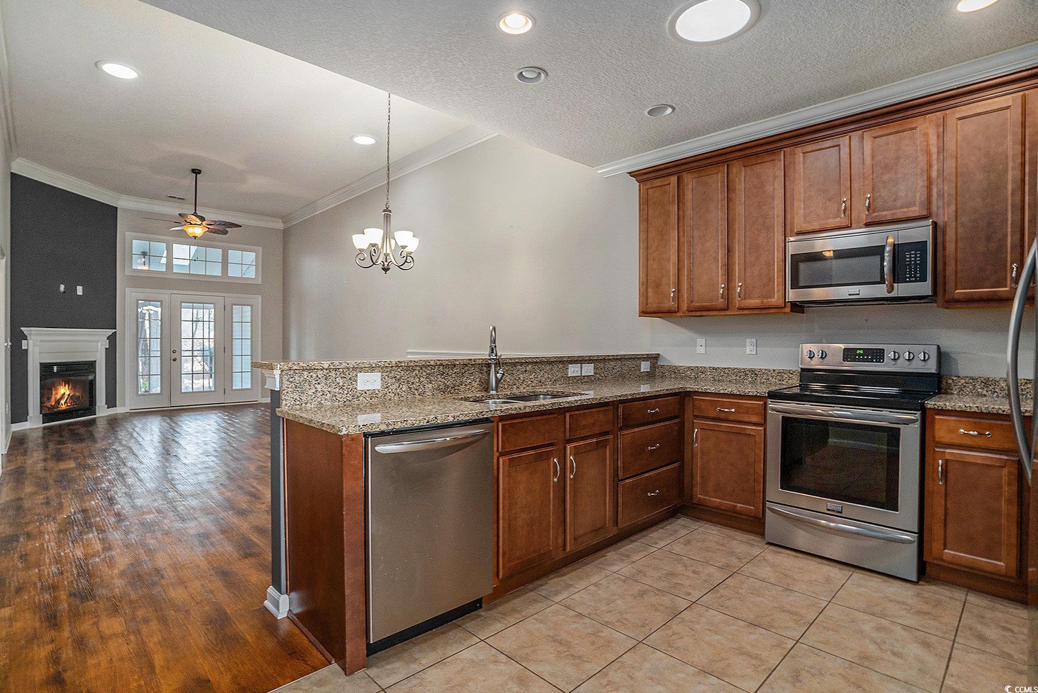1018 Red Sky Lane, Unit 101 Murrells Inlet, SC 29576 - Photo 3 of 35 Kitchen with dark stone countertops, stainless steel appliances, ornamental molding, decorative light fixtures, and a peninsula
