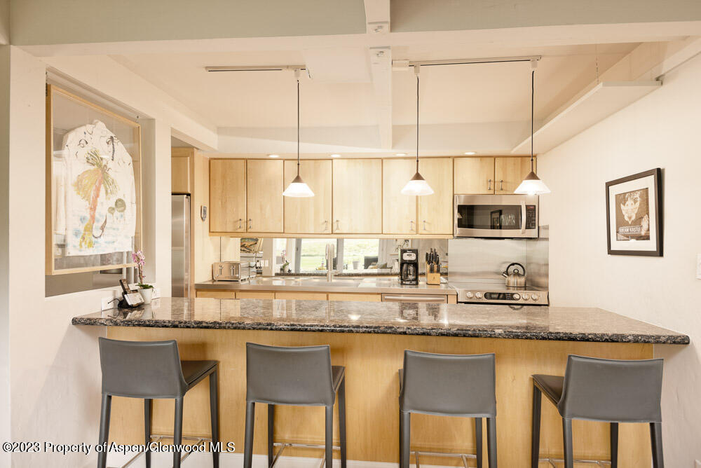 39060 Highway 82, Unit 7 Aspen, CO 81611 - Photo 6 of 17 a kitchen with kitchen island granite countertop a table chairs sink and cabinets