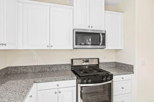 a kitchen with granite countertop white cabinets and stainless steel appliances
