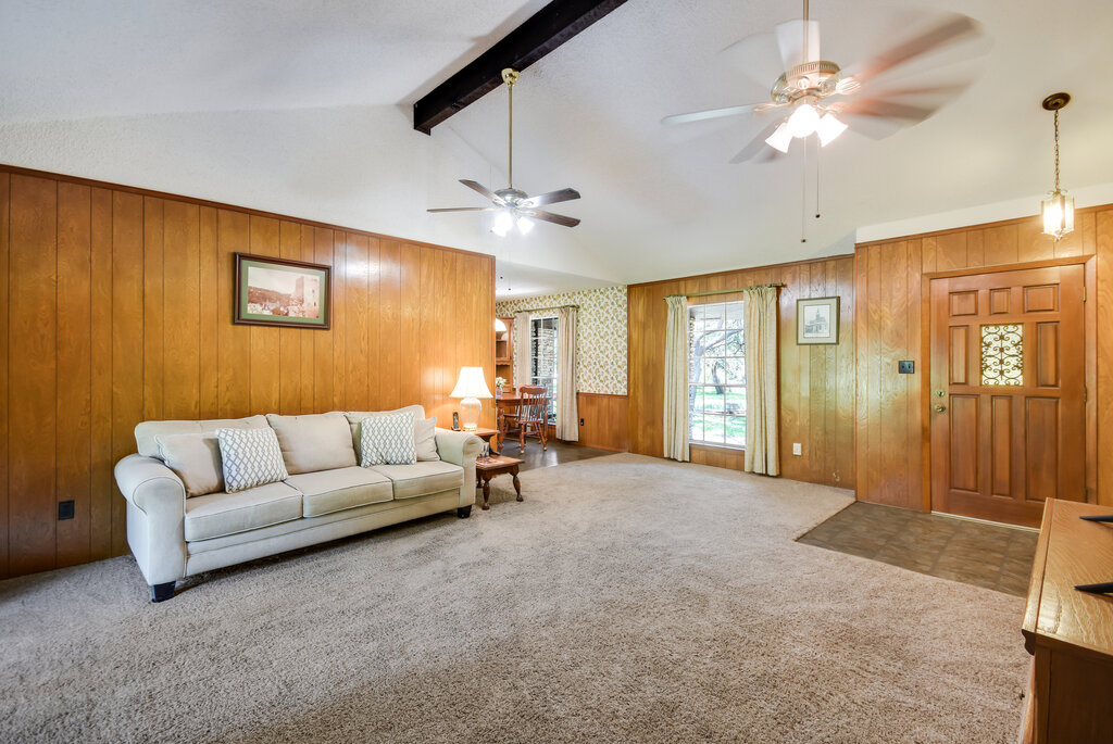 301 Navajo Trail Georgetown, TX 78633 - Photo 19 of 35 Living area with a ceiling fan, carpet flooring, and wood walls