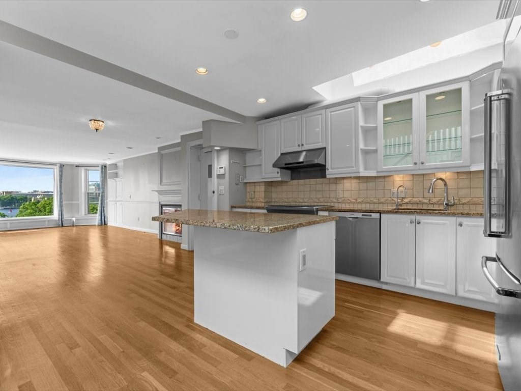 458 Beacon Street, Unit 6 Boston, MA 02115 - Photo 3 of 16 a large kitchen with kitchen island granite countertop a stove a sink a refrigerator and white cabinets with wooden floor