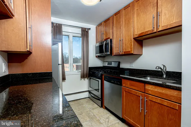 a kitchen with granite countertop wooden cabinets and a stove top oven
