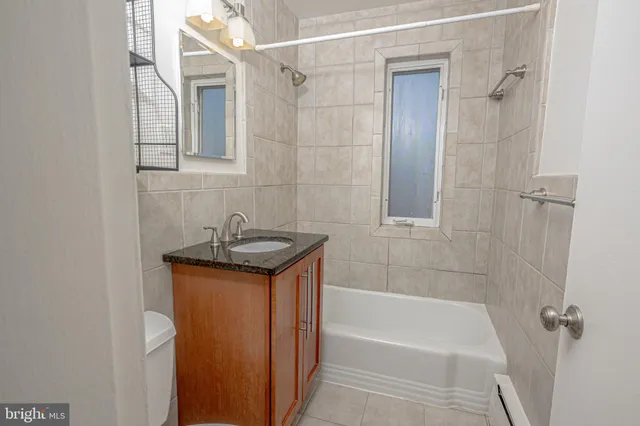 a bathroom with a granite countertop sink a mirror and a bathtub