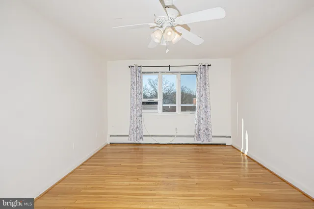 an empty room with wooden floor fan and windows