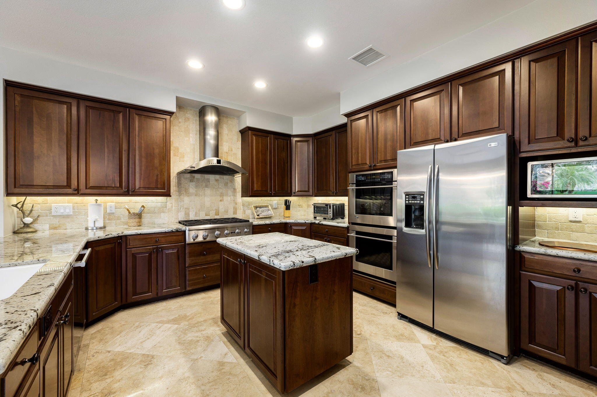 55685 Riviera La Quinta, CA 92253 - Photo 22 of 75 a kitchen with kitchen island granite countertop wooden cabinets a refrigerator and a sink