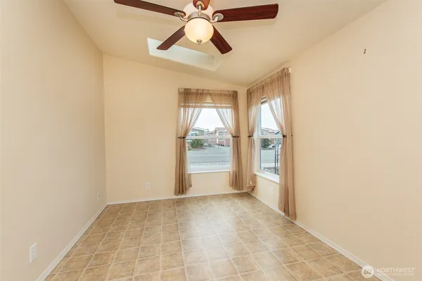 an empty room with chandelier fan and windows