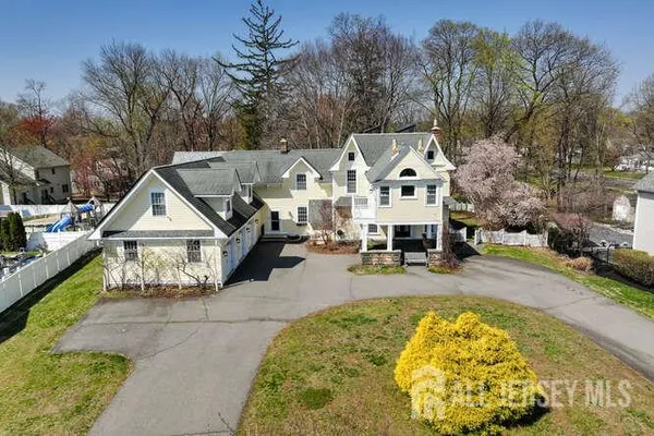 an aerial view of a house with swimming pool and large trees