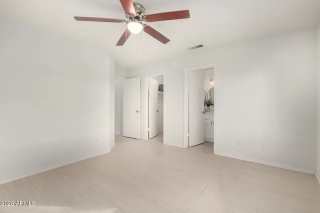 an empty room with closet and a ceiling fan