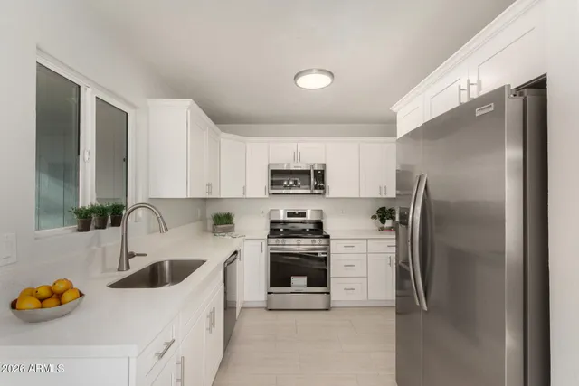 a kitchen with stainless steel appliances granite countertop a refrigerator a stove and a sink